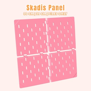 Op de afbeelding: Een roze Skadis-paneel met een raster van verticale sleuven. De tekst Skadis Panel 30 CM | 35 CM | FILES ONLY staat boven de vier verbonden vierkante panelen, die een uniform patroon van rechthoekige openingen voor organisatie bevatten.