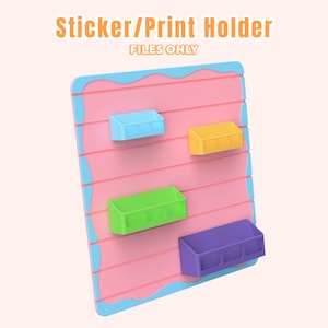 Pode incluir: Um suporte rosa e azul para autocolantes/impressões com quatro compartimentos de armazenamento multicoloridos. O texto "Sticker/Print Holder" e "FILES ONLY" é exibido na parte superior. O suporte é projetado com um padrão listrado.