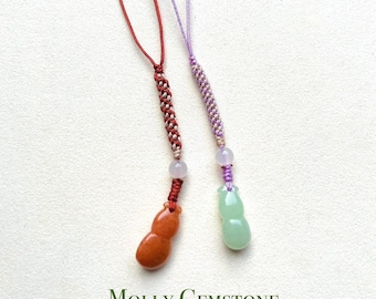 May include: Two jade gourd charms on red and purple string phone charms. The charms are tied with a knot and have a bead above the gourd. The charms are labeled "MOLLY GEMSTONE".