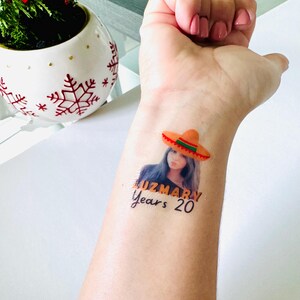 May include: A temporary tattoo showing a woman wearing a sombrero. The tattoo includes the name "LUZMARY" and the text "Years 20". The sombrero is orange with a red and green trim.