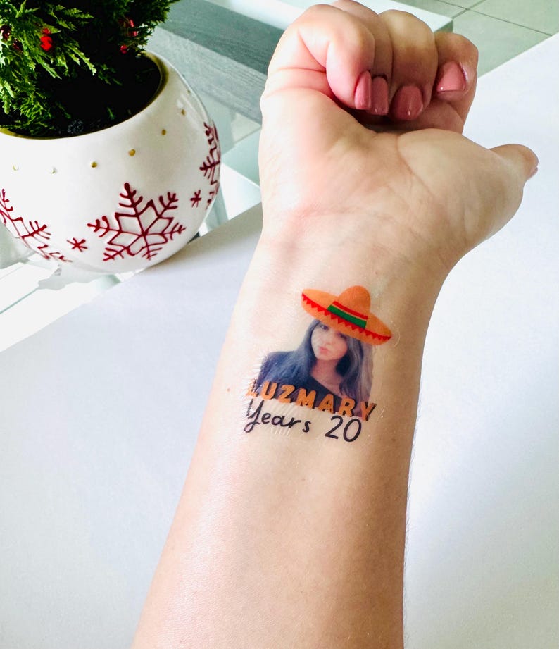 May include: A temporary tattoo showing a woman wearing a sombrero. The tattoo includes the name "LUZMARY" and the text "Years 20". The sombrero is orange with a red and green trim.