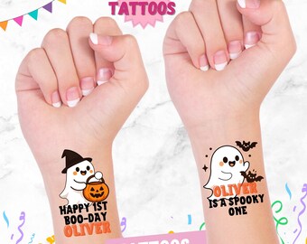 Può includere: Due polsi con tatuaggi temporanei di Halloween. Uno presenta un fantasma con un cappello da strega che tiene una zucca e il testo "Happy 1st Boo-Day Oliver". L'altro ha un fantasma con pipistrelli e il testo "Oliver is a Spooky One".