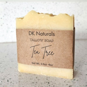 May include: A bar of yellow soap wrapped in brown paper with the text "DK Naturals Tallow Soap Tea Tree Net Wt. 3.5oz - 4oz"