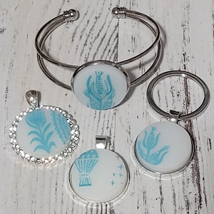 May include: A set of four blue and white ceramic pendants with different designs. The pendants are attached to silver chains and are perfect for making jewelry.