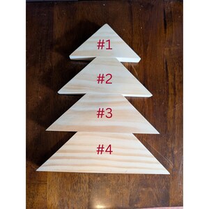 May include: Four wooden triangle shapes stacked to resemble a Christmas tree. Each triangle is a natural wood color with visible grain. The numbers #1, #2, #3, and #4 are printed in red on each triangle.