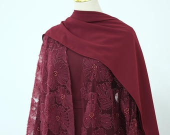May include: A deep burgundy ensemble featuring a solid-colored sleeveless dress paired with a matching sheer overlay. The overlay is adorned with large, intricate floral lace appliques and small beads, complemented by a draped burgundy headscarf.