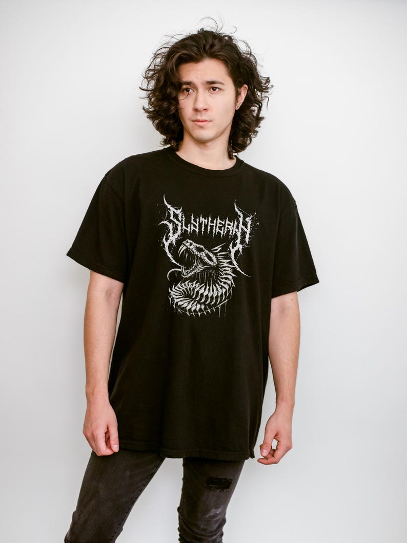 May include: A black t-shirt with a white graphic of a snake with the word "SLITHERIN" above it.