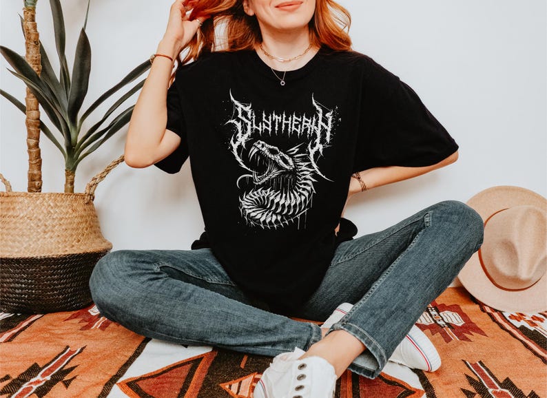 May include: Black t-shirt with a white graphic of a snake with the word "Slytherin" in a metal font.