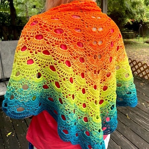 May include: A triangular crochet shawl featuring a vibrant gradient color pattern that transitions from bright orange at the top neckline down through lime green to a deep teal blue at the scalloped bottom edge with an openwork fan stitch design.