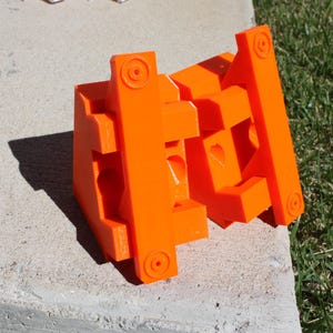 May include: A set of orange plastic building blocks, interlocking to form a geometric shape. The blocks are made of a bright orange plastic and have a smooth, glossy finish.