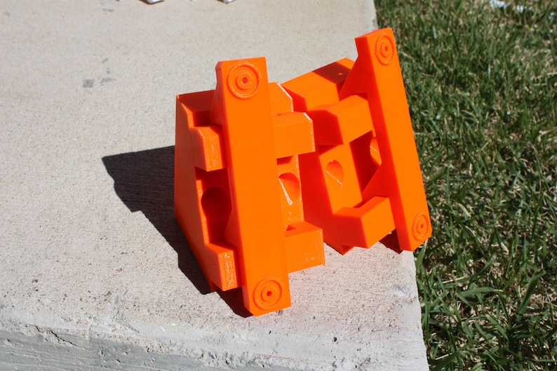 May include: A set of orange plastic building blocks, interlocking to form a geometric shape. The blocks are made of a bright orange plastic and have a smooth, glossy finish.
