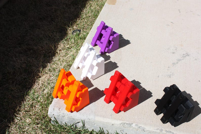 May include: Six triangular building blocks in different colours: purple, white, orange, red, black. The blocks are made of plastic and have a textured surface.