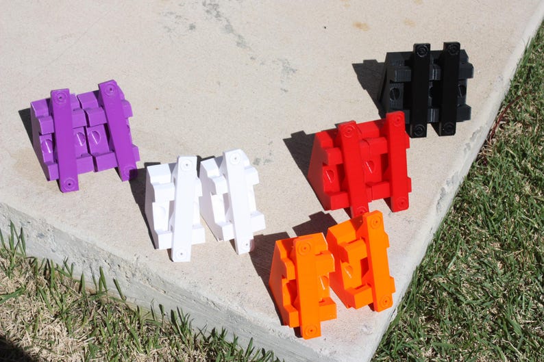 May include: Five different coloured plastic building blocks. The blocks are in the shape of a cube and are stacked on top of each other. The colours are purple, white, red, orange, and black.
