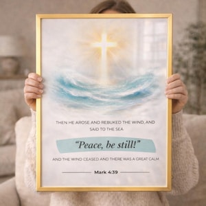 Pode incluir: Uma impressão emoldurada com uma borda dourada, apresentando uma cruz sobre ondas azuis estilizadas. O texto "Peace, be still!" está em uma faixa azul clara, com a escritura de Marcos 4:39.