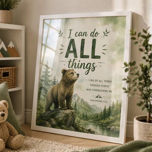 Könnte beinhalten: Weiß gerahmter Kunstdruck mit einem braunen Bären auf einem Felsen, vor einer Wald- und Flusskulisse. Grüner Text lautet "I can do ALL things" und ein Bibelvers. Der Druck wird an einer Wand ausgestellt.