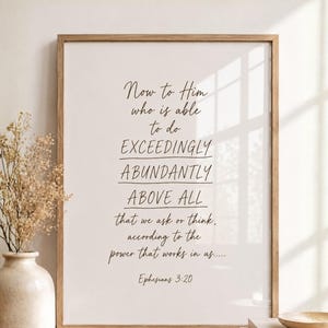 May include: A framed print featuring the text "Now to Him who is able to do exceedingly abundantly above all that we ask or think, according to the power that works in us... Ephesians 3:20." The frame is light brown.