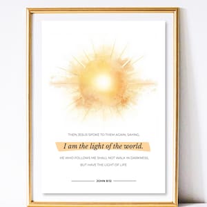 Può includere: Stampa artistica incorniciata con una cornice color oro. La stampa presenta un'esplosione solare in stile acquerello nei toni del giallo e dell'arancione. Il testo sulla stampa recita "Io sono la luce del mondo" e un versetto biblico.