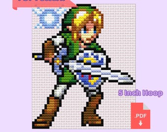 May include: A pixelated cross-stitch pattern of Link from The Legend of Zelda video game. The pattern is designed for a 5-inch hoop. The pattern includes Link holding his sword and shield, with a blue background.