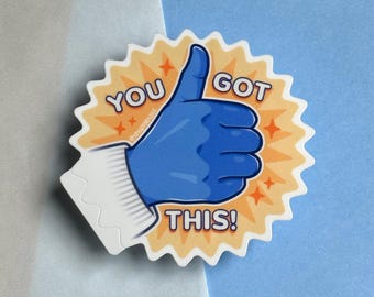 Könnte beinhalten: Ein blauer Daumen-hoch-Aufkleber mit einem gelben Sternenausbruch-Hintergrund. Der Aufkleber sagt "You Got This!" in weißer Schrift.