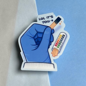 May include: A blue gloved hand holds a pH test strip with the text "LOL it's you" and a small chart showing the pH scale from 0 to 14.