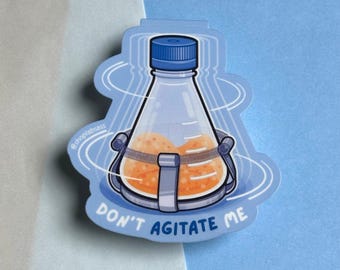 Könnte beinhalten: Ein blauer und weißer Aufkleber mit einer Cartoon-Illustration eines runden Kolbens mit einer gelben Flüssigkeit darin. Der Kolben wird geschüttelt und der Text "Don't Agitate Me" ist unter dem Kolben aufgedruckt.