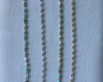 May include: Two necklaces featuring a strand of small, round, light green and pale pink beads. Each necklace includes a single, irregular, white baroque-style pearl at the bottom. One necklace has silver-toned metal links, while the other has gold-toned metal links.