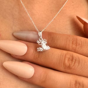 以下が含まれることがあります： シルバーの蛙ペンダントネックレス。ペンダントは、詳細な3次元のカエルデザインです。ネックレスチェーンは繊細でシルバーです。カエルペンダントの高さは約2cmです。