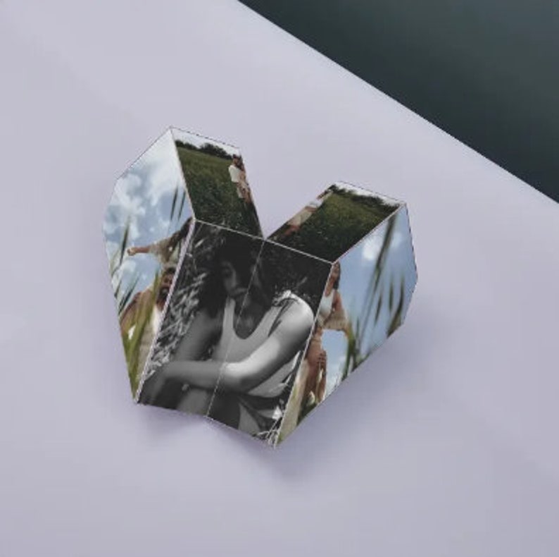 Pu&ograve; includere: Un cubo fotografico a forma di cuore con sei lati, ognuno con un'immagine diversa di persone in un campo. Le immagini sono in bianco e nero e a colori.