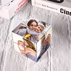 Pu&ograve; includere: Un cubo fotografico con sei immagini diverse di una famiglia. Il cubo &egrave; in metallo e ha una finitura argentata. Le foto mostrano una madre e i suoi due figli.