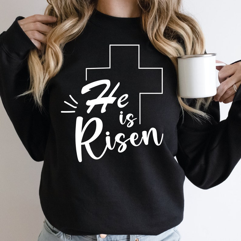 May include: Black sweatshirt with a white graphic design of a cross and the text "He is Risen".
