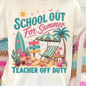 Pode incluir: Camiseta creme com um gráfico com tema de praia. O design inclui o texto "SCHOOL OUT For Summer TEACHER OFF DUTY" em verde-azulado e rosa, juntamente com ilustrações de uma prancha de surf, cadeira de praia, palmeira e outros elementos de verão.