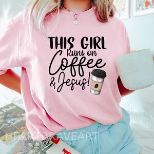 May include: Pink t-shirt with the text "This Girl Runs on Coffee & Jesus!" and a graphic of a coffee cup.