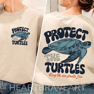May include: A beige sweatshirt with a graphic print of a sea turtle and the text "Protect the Turtles. Keep the sea plastic free."