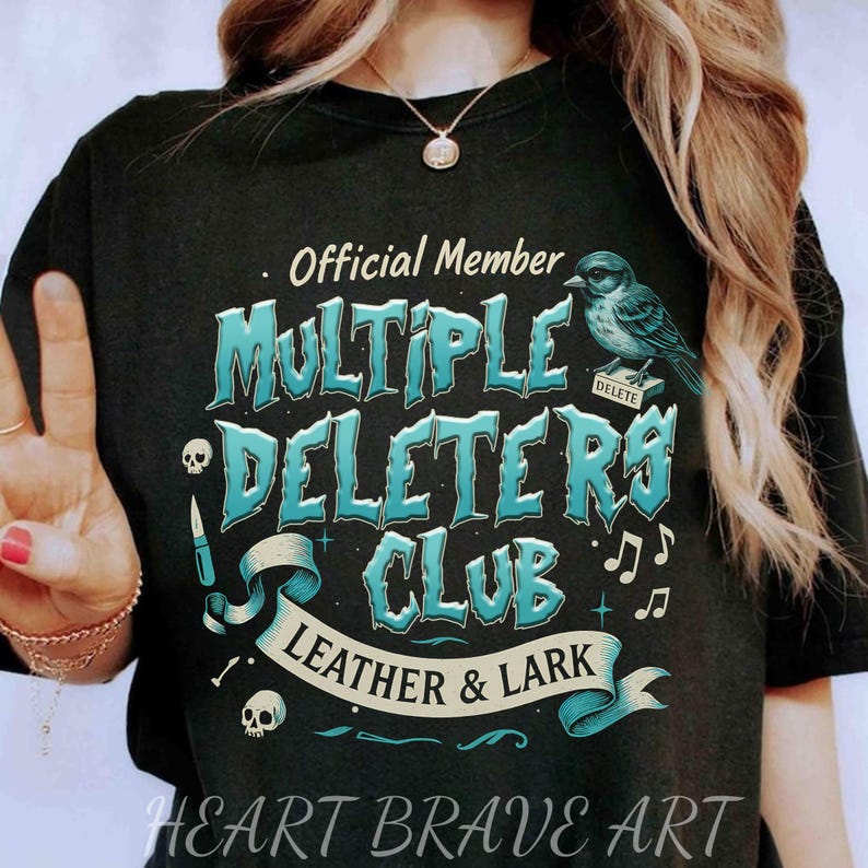 May include: Black t-shirt with a blue and white graphic design that says "Official Member Multiple Deleters Club Leather & Lark" with a bird and musical notes. The text "Heart Brave Art" is at the bottom of the shirt.