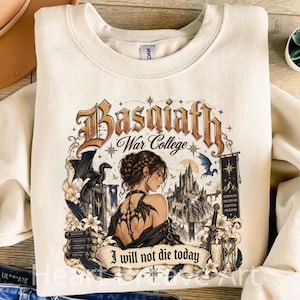 May include: A cream-colored crewneck sweatshirt featuring a graphic print with the text Basaiath War College and I will not die today. The design includes a person with a back tattoo, a castle, a dragon, a sword, and a stack of books.