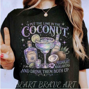 May include: A black t-shirt featuring a graphic print with the text "PUT THE LIME IN THE COCONUT" and "AND DRINK THEM BOTH UP". The design includes a tequila bottle, a margarita glass, a shot glass, a coconut, and a lime slice with stars.