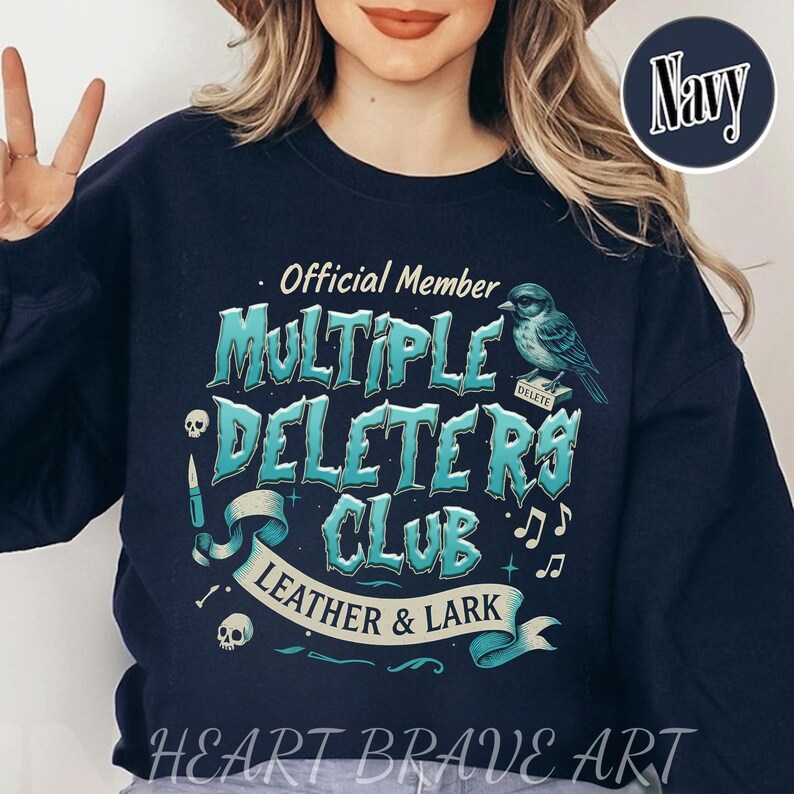 May include: A navy blue sweatshirt with a graphic design that says "Official Member Multiple Deleters Club Leather & Lark". The graphic features a blue bird with a "Delete" tag on its leg, musical notes, and skulls.