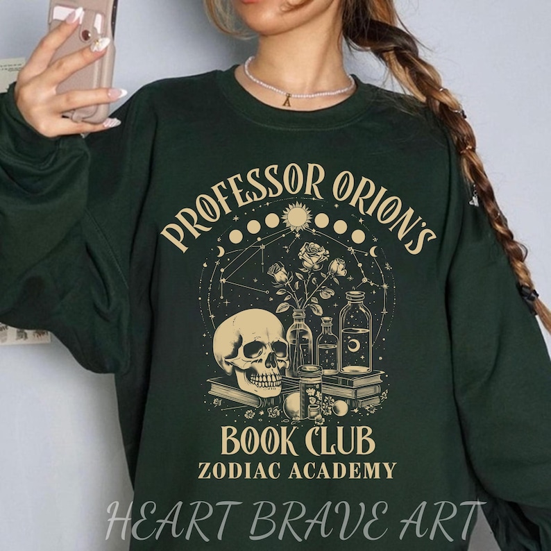 May include: Green sweatshirt with a graphic design featuring a skull, flowers, and bottles. The text "Professor Orion's Book Club Zodiac Academy" is printed on the sweatshirt.