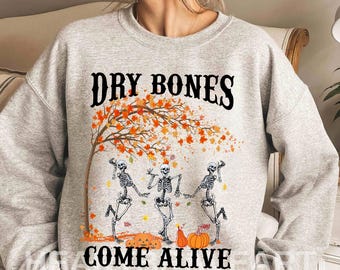 May include: Gray sweatshirt with a graphic of three skeletons dancing under a fall tree with the text "Dry Bones Come Alive".