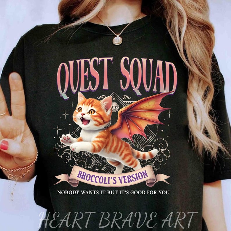 May include: Black t-shirt with a graphic of a cat with wings. The text "QUEST SQUAD" is above the cat and "BROCCOLI'S VERSION" is below the cat. The text "NOBODY WANTS IT BUT IT'S GOOD FOR YOU" is below the graphic.