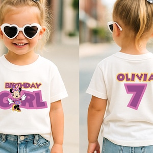 May include: A white short-sleeved t-shirt featuring a graphic of Minnie Mouse with the text Birthday Girl on the front. The back of the shirt displays the name Olivia in yellow letters above a large purple number 7 with a yellow outline.