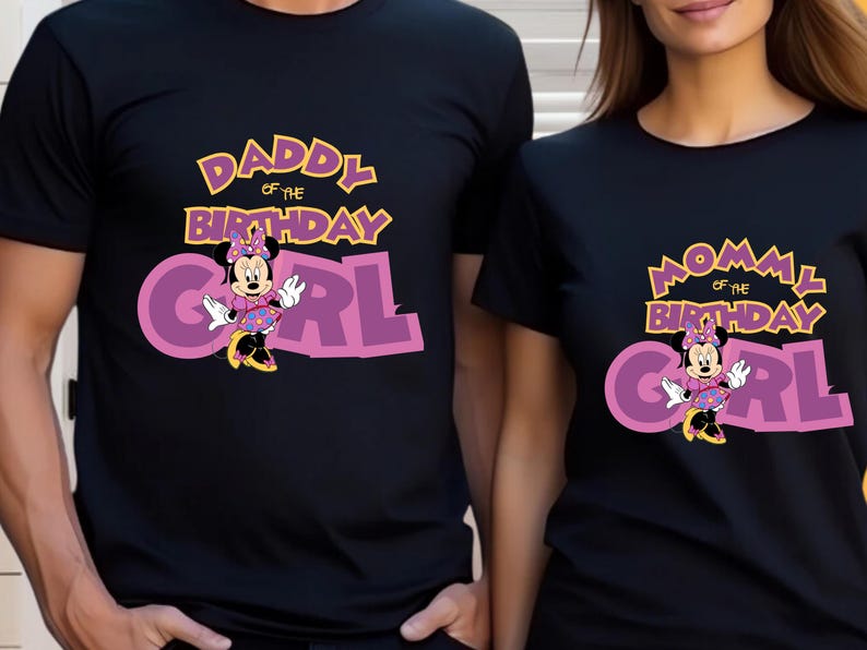 May include: Two black short-sleeved t-shirts featuring a graphic of Minnie Mouse. One shirt displays the text DADDY OF THE BIRTHDAY GIRL in yellow and purple, while the other shirt displays the text MOMMY OF THE BIRTHDAY GIRL in the same colors.