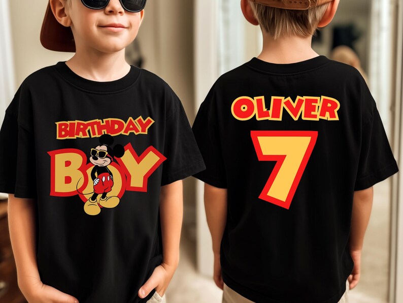 May include: A black t-shirt featuring a graphic of Mickey Mouse wearing sunglasses with the text BIRTHDAY BOY on the front. The back of the shirt displays the name OLIVER in red letters above a large yellow number 7 with a red outline.