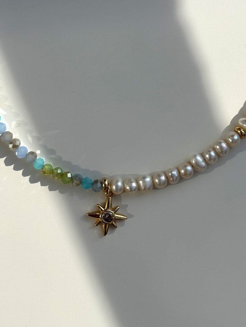 May include: A delicate necklace with a gold star charm and a mix of blue and white beads.