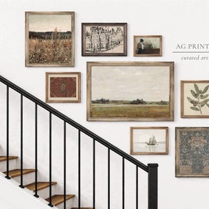 Peut inclure: Une collection d'estampes d'art vintage encadrées de différentes tailles et styles, comprenant des paysages, des paysages urbains et des illustrations botaniques. Les estampes sont exposées sur un mur blanc près d'un escalier avec une rampe noire. L'œuvre est de AG PRINTS CO.