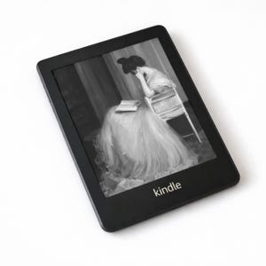 May include: Black Kindle e-reader displaying a grayscale image of a woman reading. The e-reader has a rectangular shape with rounded corners and the word "kindle" printed at the bottom. The screen shows a woman in a long dress.