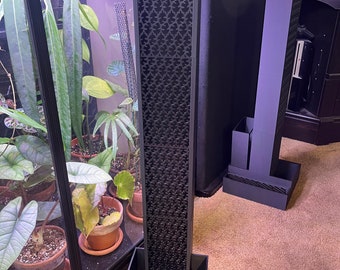 May include: A black metal air purifier with a geometric pattern on the front. The purifier is sitting in a black square planter.