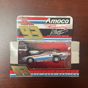 Puede incluir: Una réplica de coche de carreras a escala 1:64 de color blanco y azul con las palabras "Amoco Racing" y "Ultimate" en el lateral. El coche está en una caja con el número "93" en ella.