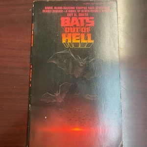 Op de afbeelding: Een paperback boekomslag met een rode en zwarte illustratie van vleermuizen die uit een vurige hel vliegen. De titel van het boek is "Bats Out of Hell" door Guy N. Smith.