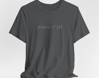 Könnte beinhalten: Dunkelgraues T-Shirt mit dem Schriftzug "peace y'all" in Hellgrau auf der Brust. Das T-Shirt hat kurze Ärmel und einen Rundhalsausschnitt.